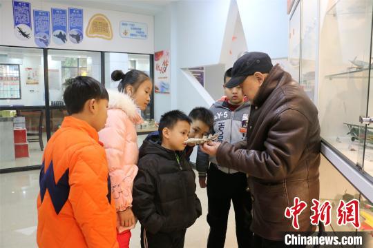 杨腾祥给孩子们展示其制作的飞机模型。　林馨　摄