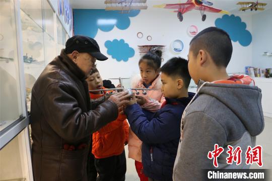 杨腾祥给孩子们展示其制作的飞机模型。　林馨　摄