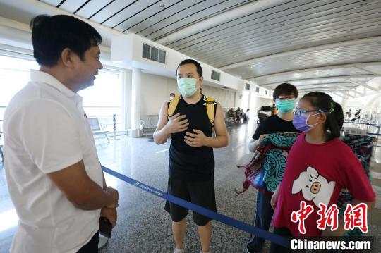 中国侨网图为中国驻登巴萨总领事苟皓东（左）与乘包机回国游客亲切交谈。（林永传／摄）