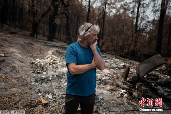 当地时间1月16日，澳大利亚冲浪者大卫·福特站在一片废墟旁满脸愁容。被烧毁的屋子他用来存放自己收藏的老式冲浪板，山火过后，这里只剩下灰烬。