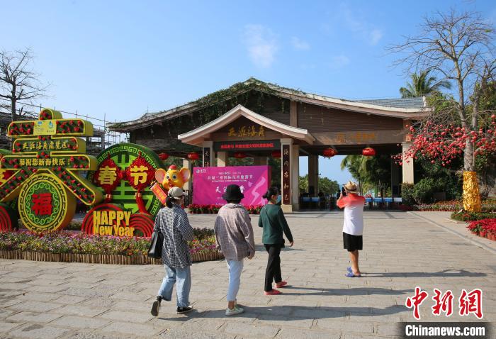 21日在天涯海角游览区，游客走过景区大门前的春节装饰物。　王晓斌 摄