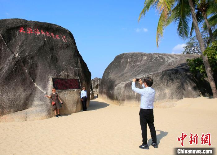 图为21日在天涯海角游览区，游客在景区标志性景点“天涯石”前留影。　王晓斌 摄