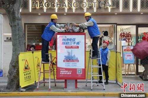 中国侨网中国电信的工作人员正在电话亭的顶盖内安装调试5G微基站。　张亨伟　摄