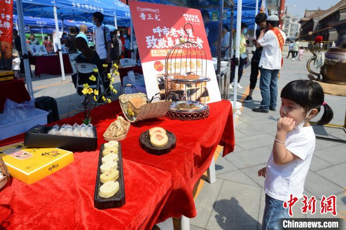 6月12日，一位小朋友在呼和浩特老字号美食摊位前驻足。　刘文华 摄