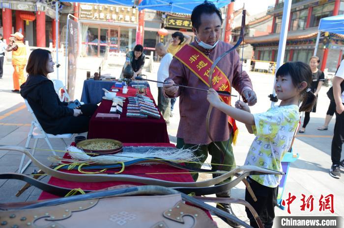 6月12日，蒙古族传统角弓制作技艺非遗传承人诺敏教授小朋友射箭技巧。　刘文华 摄