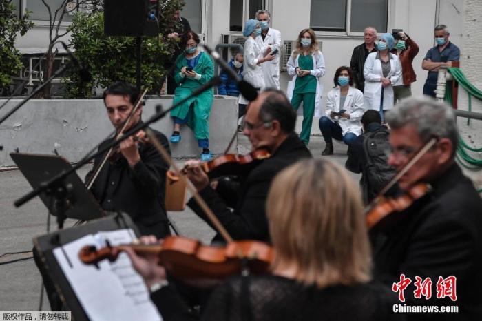 当地时间4月20日，新冠疫情期间，希腊雅典福音医院的医务人员在院子里聆听希腊国家广播交响乐团的音乐会。