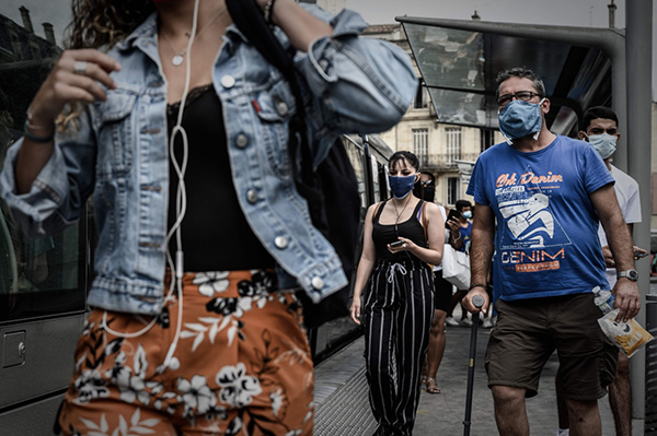 7月20日，行人戴着口罩走过法国波尔多一个有轨电车车站。新华社 图