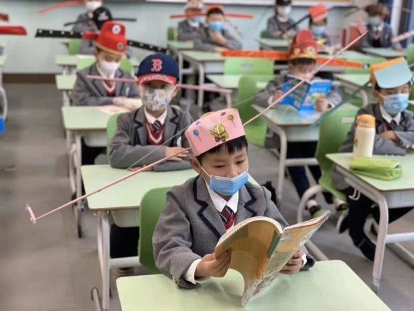 中国杭州一小学，结束疫情后回校上课，老师为每个人设计的帽子。每一顶帽子的两侧有长长的帽翅，以表示一种安全的社交距离。有趣的是，早在中国宋代就有相似的帽子（长翅帽），避免朝臣们在朝堂上交头接耳。