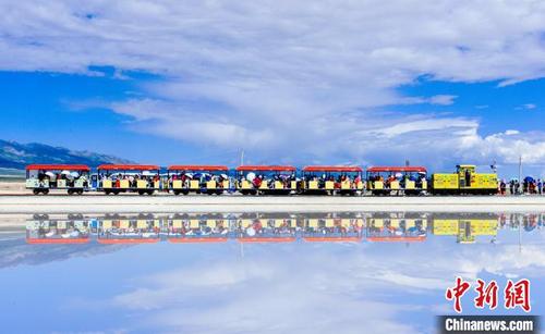 中国侨网图为游客在“天空之镜”青海茶卡盐湖乘小火车游览。杨金花摄