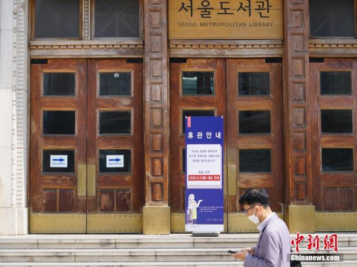 6月23日，一位韩国首尔市民经过首尔市立图书馆门前，该图书馆贴出闭馆通知。