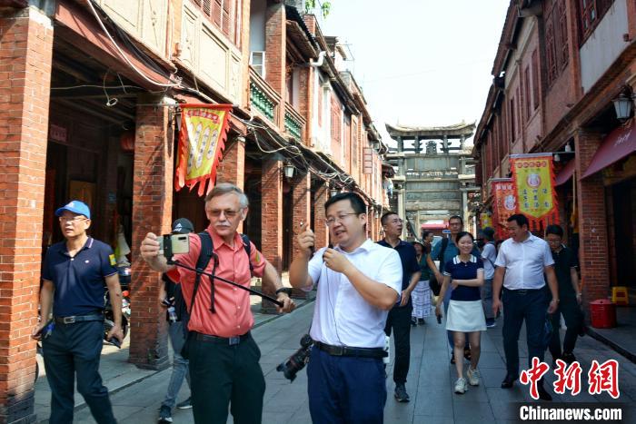 潘维廉(左二)手持自拍杆畅游漳州古城，了解漳州古城的历史文化、建筑特色、民俗风情。　龚雯 摄