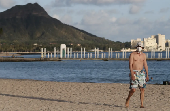 △一名游客戴着口罩在夏威夷威基基海滩散步。 图片来源：路透社