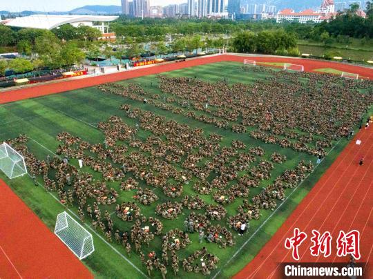 中国侨网4000多名新生和军训官兵身着迷彩服，席地而坐，快乐博饼。厦大嘉庚学院供图
