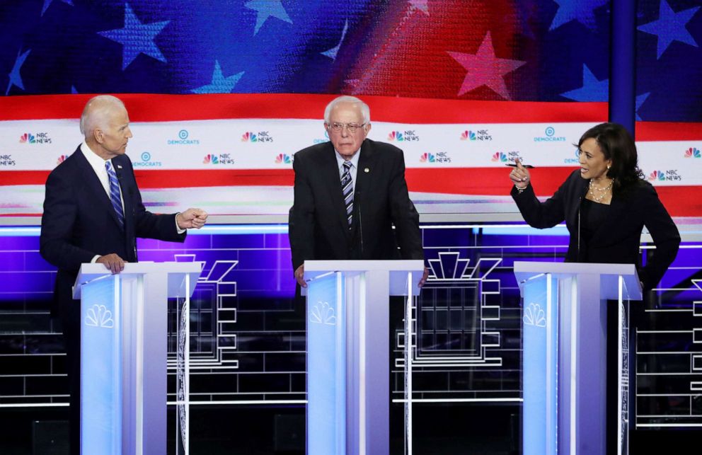 PHOTO: Former Vice President Joe Biden and Sen. Kamala Harris and speak as Sen. Bernie Sanders looks on during the first Democratic presidential debate in Miami, June 27, 2019.