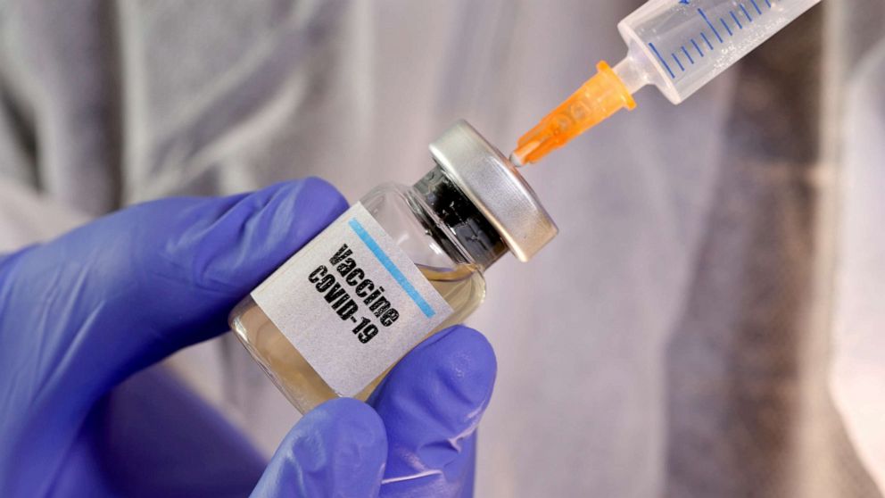 PHOTO: A medical syringe is inserted into a small bottle labeled 