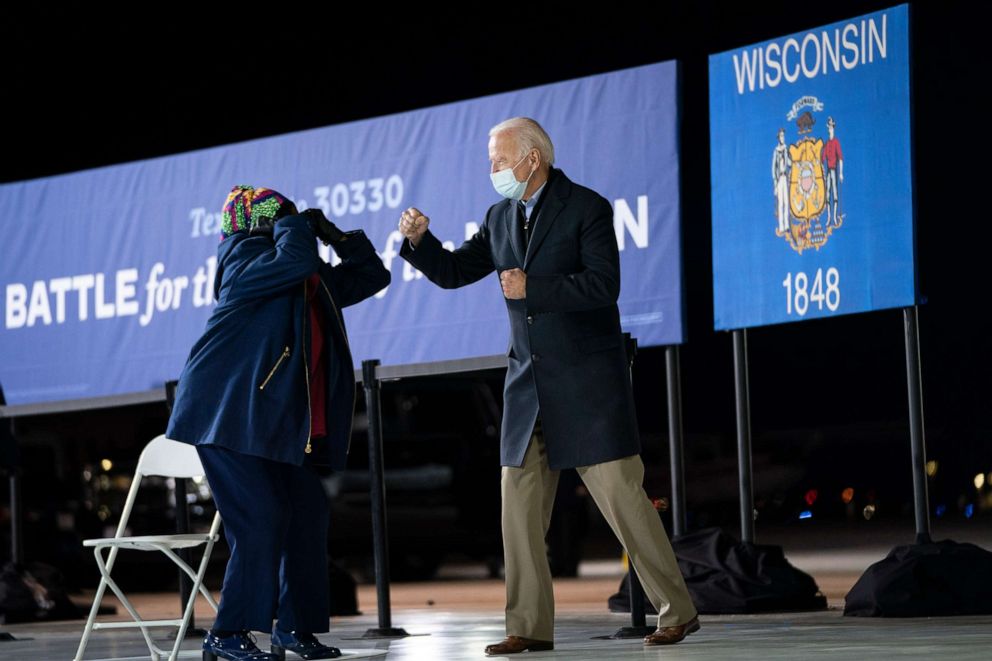 PHOTO: Democratic presidential nominee Joe Biden gives a fist bump to Rep. Gwen Moore, D-Wis., as he arrives to speak at Milwaukee Mitchell International Airport on Oct. 30, 2020, in Milwaukee.