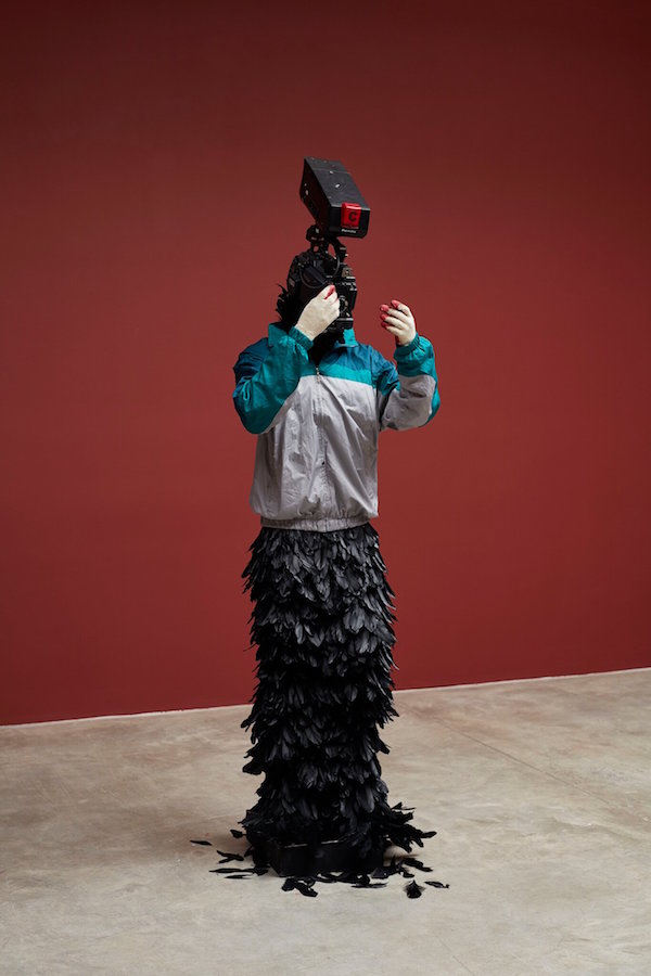 韩国艺术家Minouk Lim的作品“ L’hommeàlacaméra”（2015年），该作品是由玻璃纤维增强的塑料风衣，人体模型，手套，羽毛和摄像机组成。