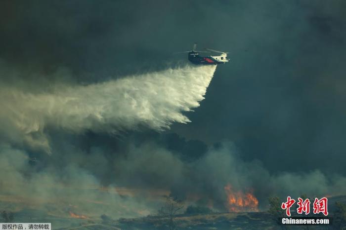 当地时间12月3日，美国加利福尼亚州橙县附近山火蔓延。图为飞机赶赴火场洒水救援。