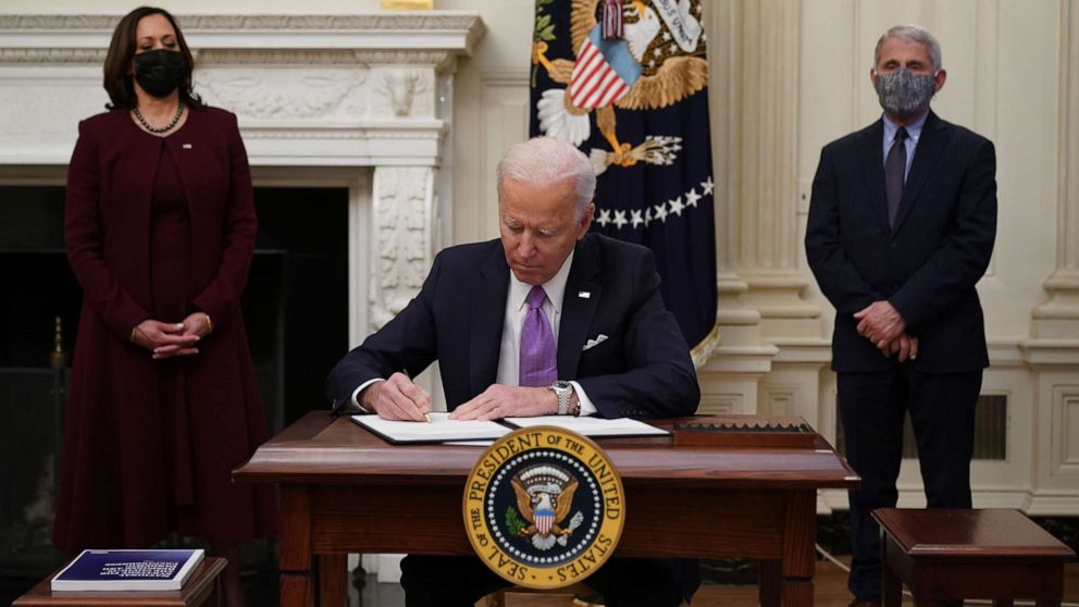 PHOTO: President Joe Biden signs executive orders as part of the COVID-19 response as Vice President Kamala Harris and Director of NIAID Anthony Fauci look on in the State Dining Room of the White House in Washington, D.C., Jan. 21, 2021.