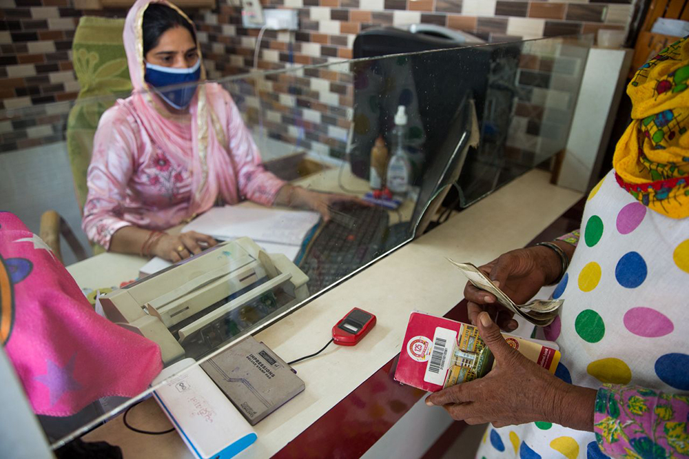 印度西拉那，一名业务经理在帮助一名女性办理银行业务。图片来源：©Gates Archive_Mansi Midha