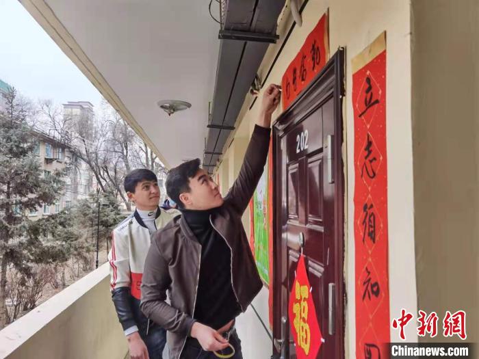 图为青海民族大学留学生在宿舍门口贴春联。　潘雨洁 摄