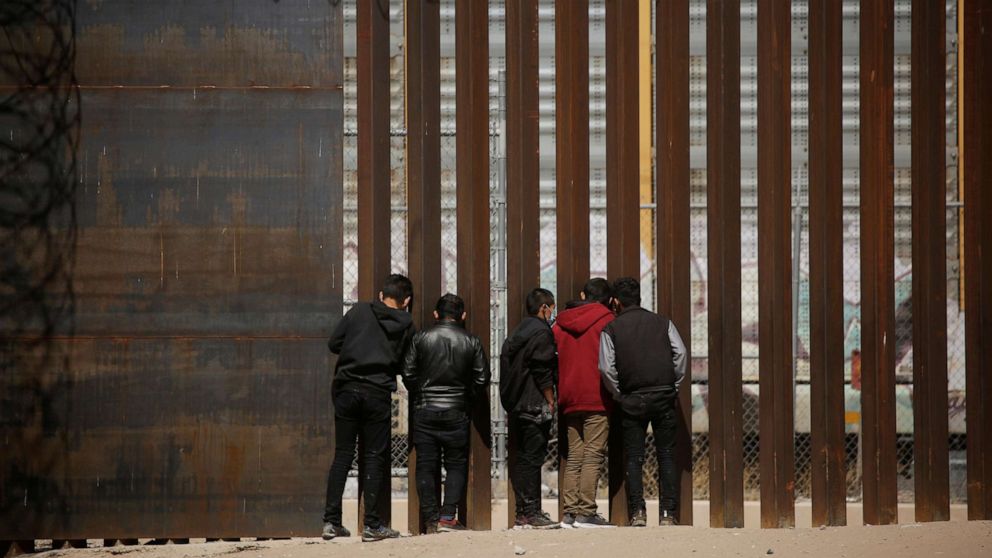 PHOTO: Migrants look through the border wall after crossing the Rio Bravo river to turn themselves in to U.S. Border Patrol agents and request asylum in El Paso, Texas, U.S., as seen from Ciudad Juarez, Mexico March 14, 2021. 