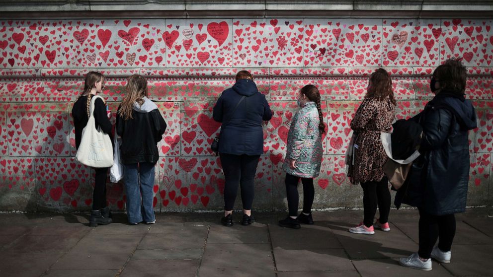 PHOTO: People stand by the National Covid Memorial wall beside St Thomas' hospital set as a memorial to all those who have died so far in the U.K. from the coronavirus disease, in London, April 8, 2021.