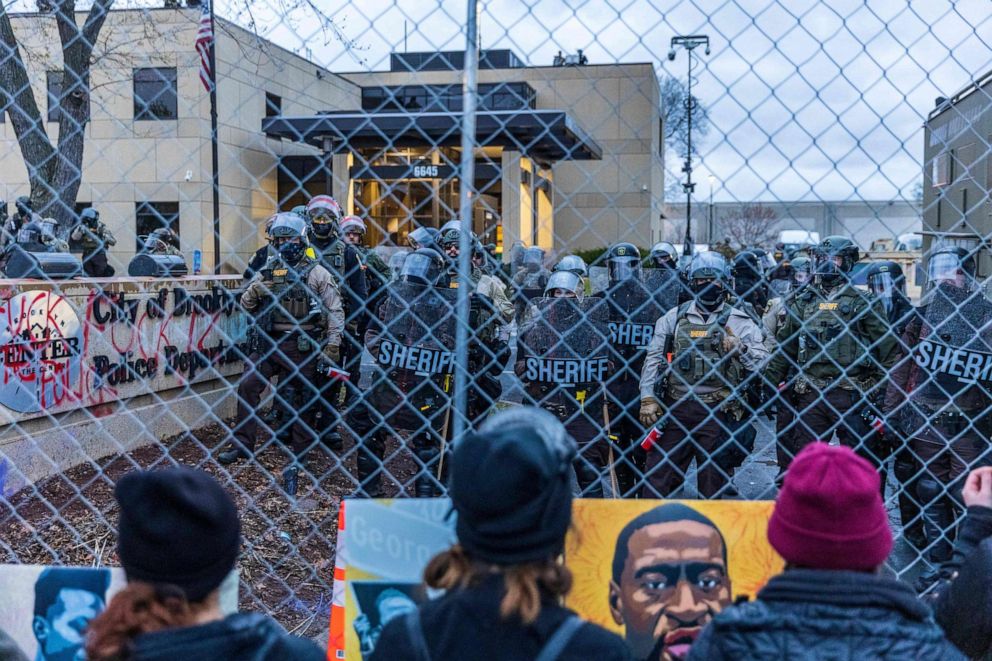 PHOTO: Law enforcement officers stand guard outside the Brooklyn Center Police Department as demonstrators stand on the other side of the fence in Brooklyn Center, Minnesota, on April 14, 2021, amid protests over the fatal shooting of Daunte Wright.