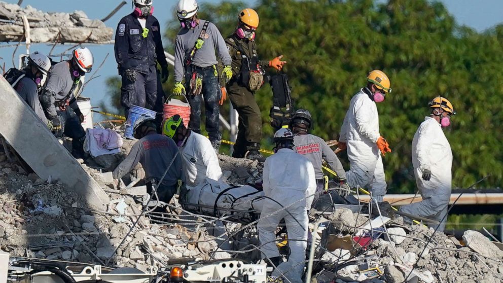 PHOTO: Search and rescue personnel remove remains on a stretcher as they work atop the rubble at the Champlain Towers South condo building where scores of people remain missing more than a week after it partially collapsed, July 2, 2021, in Surfside, Fla.