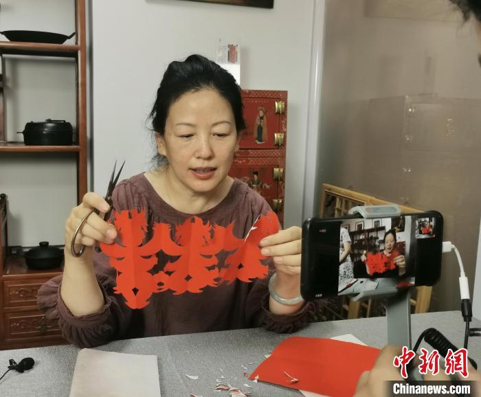 山西省民间剪纸艺术家协会会长郭梅花正在认真地教着海外华裔青少年剪纸。　杨杰英 摄