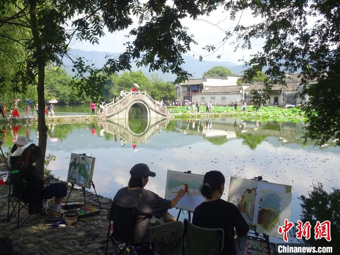 大批写生游客围坐在黟县宏村景区南湖畔写生绘画。　吴寿宜 摄