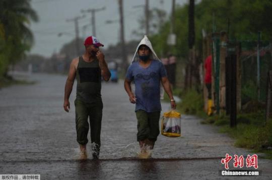 当地时间8月28日，飓风“艾达”登陆古巴，带来强风降雨天气，古巴阿尔特米萨省Guanimar部分道路被淹。图为行人走在被雨水淹没的街道上。