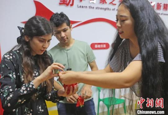 图为社区志愿者(右一)带领燕山大学外国留学生体验制作香囊。　曹建雄 摄