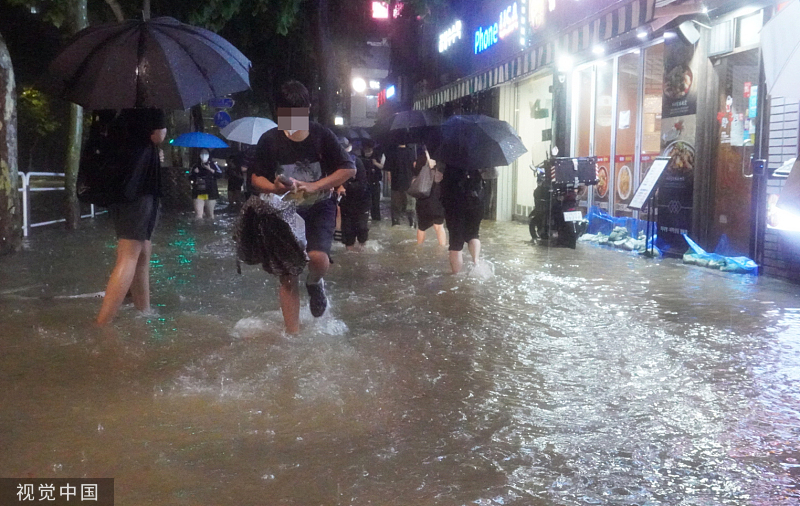 当地时间2022年8月8日晚，韩国首尔，江南区银马公寓附近，学生们正在通过被水淹没的道路回家。视觉中国 图