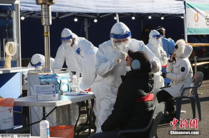 资料图：韩国首尔，医务人员对一名市民进行新冠病毒检测。