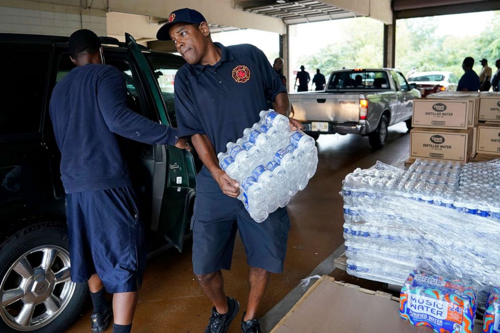 PHOTO: A firefighter puts cases of bottled water in a resident's SUV at the Fire Station as part of the city's response to longstanding water system problem in Jackson, Miss., Aug. 18, 2022.