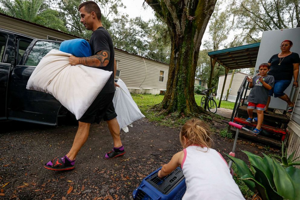 PHOTO: Allen Silke, 33, left, helps his brother's family, Isabella, 4, JP, 8 and Heather, 35, load their belongings into vehicles as they evacuate their home before Hurricane Ian makes landfall in Tampa, Fla., Sept. 27, 2022