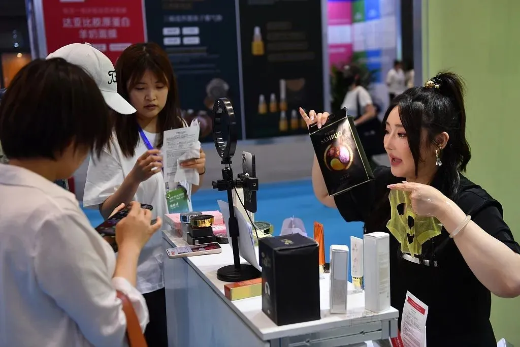 2023年6月21日，青岛，在日韩进口商品博览会上，一名工作人员在直播销售韩国产面膜。
