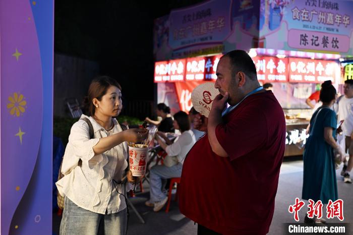 中国侨网4月22日晚,“舌尖上的海珠——食在广州嘉年华”在广州市海珠区保利广场举行。图为参加第137届广交会的境外采购商(右一)逛美食市集。中新社记者 陈楚红 摄