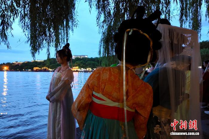 中国侨网8月6日,游客身穿传统服饰在西湖边留影。当日,浙江杭州,傍晚的西湖景色美如画,吸引游客打卡。中新社记者 钱晨菲 摄